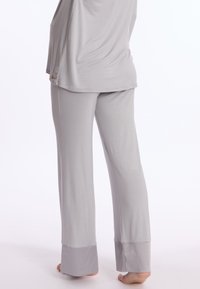 Ensemble de vêtements de détente gris comprenant un haut à manches longues et un pantalon à coupe décontractée. Tissu doux avec une texture lisse. Pantalon avec ourlets resserrés.