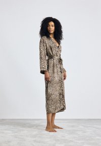 Robe en imprimé léopard en tissu doux, à manches longues, taille cintrée, longueur genou, avec un décolleté en V profond et des poches avant.