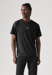 Tricou negru din bumbac cu un logo roșu Levi's pe piept. Designul este cu mâneci scurte și are un decolteu rotund clasic.