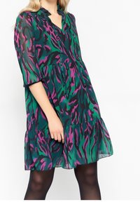 Šaty s krátkým rukávem a véčkovým výstřihem v zeleno-fialkovém zvířecím potisku, s vrstveným volánkovým lemem a lehkou, splývavou texturou látky.