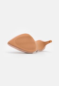 Chaussure à talon haut rose-beige avec un bout pointu, dessus lisse et semelle beige texturée avec des rainures pour une meilleure adhérence.