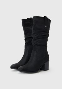 Schwarze Knöchelstiefel mit einem weich fallenden Design, aus weichem Stoff. Sie verfügen über einen Blockabsatz und ein dezentes Logo-Detail an der Seite.