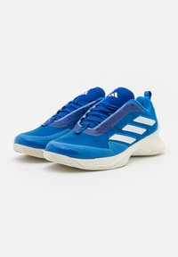 Scarpe da ginnastica blu con una combinazione di superfici lisce e testurizzate, dotate di strisce bianche, punta arrotondata e suole imbottite.