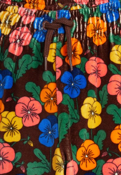 Κοντινή λήψη καφέ υφάσματος με πολύχρωμο floral μοτίβο και καφέ κορδόνι δεμένο σε κόμπο στη μέση.