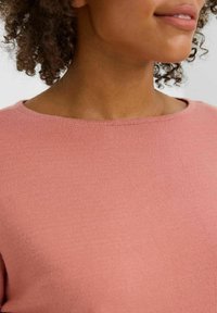 Rosa Pullover mit rundem Ausschnitt und einem weichen, strukturierten Stoff. Das Design ist schlicht mit glattem Finish und minimalen Details.