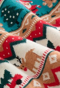 Pletená deka s vianočným motívom sobov, vianočných stromčekov a geometrických vzorov v odtieňoch červenej, zelenej, bielej a hnedej.