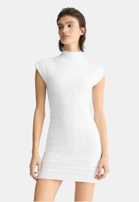 Abito bianco aderente con collo alto e maniche corte, caratterizzato da decorazioni testurizzate e una finitura di tessuto liscia.