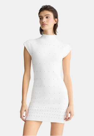 Abito bianco aderente con collo alto e maniche corte, caratterizzato da decorazioni testurizzate e una finitura di tessuto liscia.