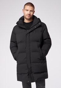 Cappotto invernale nero con collo alto, grandi sezioni trapuntate, zip frontale, bottoni a pressione e tasche laterali; realizzato in materiale isolamento e resistente all'acqua.