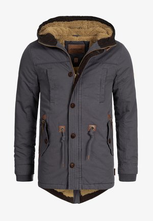 Grå jacka med ett texturerat, brunt fuskpälsfoder. Den har huva med dragsko, dragkedjeförsedda fickor och träknappar. Bruna läderdetaljer.