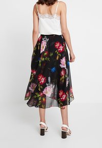 La falda midi floral presenta un tejido negro transparente con coloridas flores en tonos rosa, azul y verde. Termina con una cinturilla elástica y un diseño fluido.