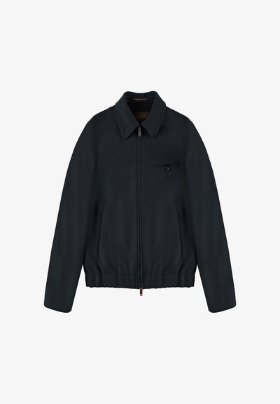 Marineblaues Reißverschlussjackett mit klassischem Kragen, seitlichen Taschen und einer Brusttasche. Glatte Textur, minimalistisches Design und dezente Hardware-Details.