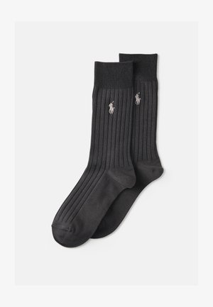 Calcetines de color gris oscuro con un diseño acanalado, hechos de un material suave, que presentan un pequeño logo bordado en gris claro. El diseño incluye una puntera y un talón reforzados.