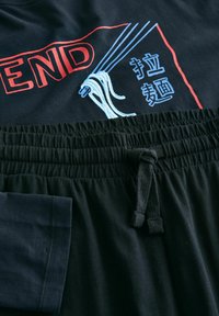 Zwart katoenen t-shirt met rode en blauwe graphics van noedels en Chinese tekst. Zwarte katoenen sweatpants met elastische tailleband en trekkoord.