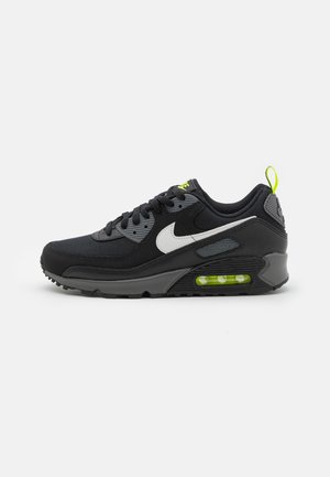 Le sneaker Nike Air Max 90 nere presentano una tomaia in rete e sintetico, con il logo Swoosh bianco, dettagli grigi e una soletta di ammortizzazione verde lime.