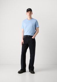 Light blue cotton t-shirt, dark denim jeans, black shoes, and a black cap with white text. Simple design and relaxed fit.