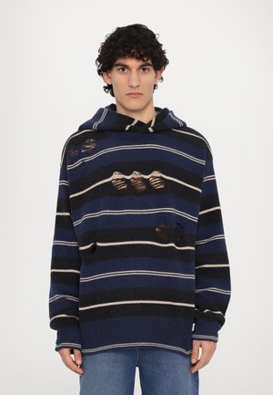 Kapuzensweater aus Strickstoff mit dunkelblauen, navy und cremefarbenen Streifen, verziert mit abgetragenen Patches und einem lockeren Schnitt.