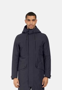Parka impermeável azul marinho com capuz, cordões ajustáveis, bolsos frontais e punhos com botão de pressão. Textura suave, design minimalista.