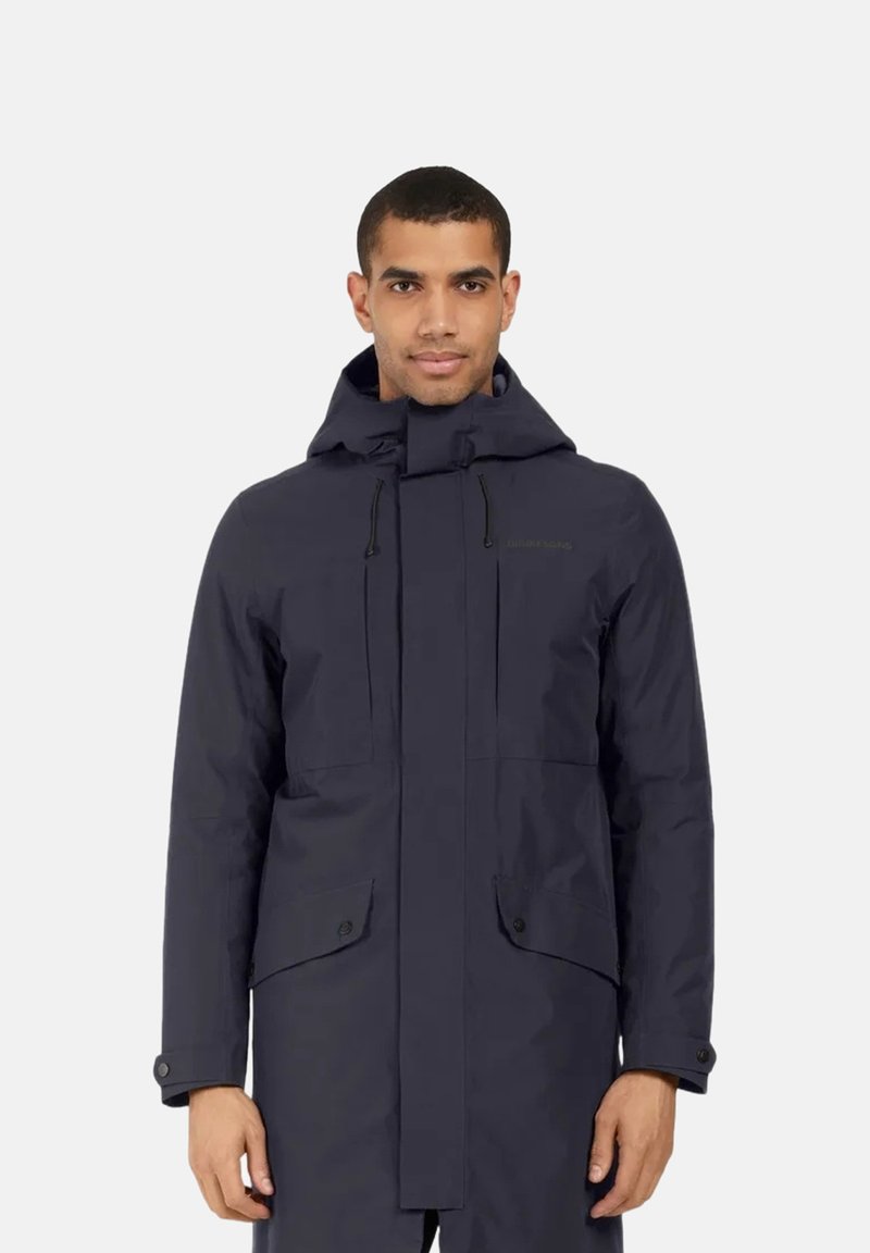 Parka impermeável azul marinho com capuz, cordões ajustáveis, bolsos frontais e punhos com botão de pressão. Textura suave, design minimalista.