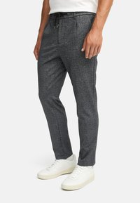 Mørk grå smale bukser laget av teksturert stoff, med elastisk midjebånd og snor samt sidelommer.