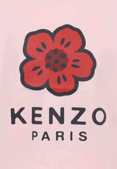 Chemise rose avec un graphisme de fleur rouge et des accents noirs. En dessous, le nom de la marque "KENZO" et "PARIS" en lettres noires en gras.