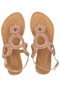 Sandali piatti con una soletta in faux suede marrone, decorati con perline circolari rosa chiaro e motivi ritagliati decorativi. Cinturino alla caviglia regolabile.