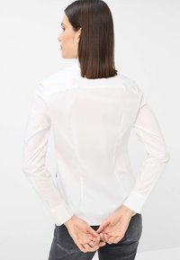 Weißes Langarmhemd mit tailliertem Schnitt und glatter Textur. Verfügt über einen klassischen Kragen und geknöpfte Manschetten, von hinten betrachtet.