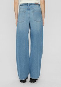 Hellblaue weite Jeans mit hoher Taille, ausgestattet mit einer klassischen Denim-Textur, Gesäßtaschen und subtiler Verwaschung. Mit einem rohen Saum versehen.