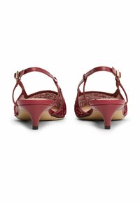 Sandales à talons rouges en cuir avec un motif tissé, une bride de cheville et un petit talon conique. Texture lisse et rembourrage léger visible à l'intérieur.