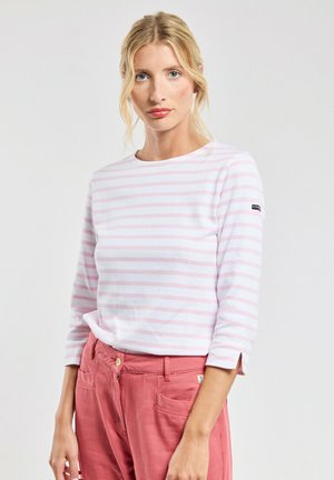 Haut à rayures à manches longues en coton rose clair et blanc, avec un décolleté bateau et des fentes sur les côtés. Associé à un pantalon taille haute rose.