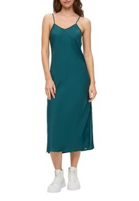 Turkusowa midi sukienka z gładkiego materiału, z cienkimi ramiączkami i rozcięciem z boku, zestawiona z białymi sneakersami za kostkę.