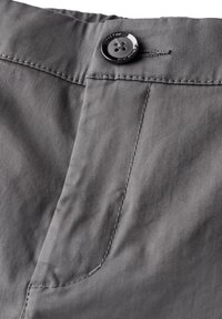 Grått tyg med en slät textur som har en knappstängning och kontrasterande sömmar längs fickan och midjebandet.