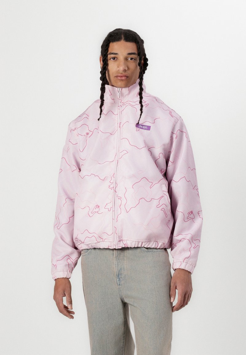 Pink jacket with a wave pattern, featuring a high collar and zip closure. Elastic cuffs and hem, paired with light blue jeans.