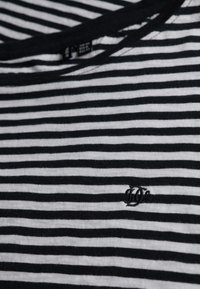 Czarny i biały t-shirt w paski, wykonany z miękkiego materiału, z okrągłym dekoltem i małym haftowanym logo z przodu.