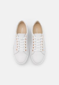 Baskets blanches avec une tige en cuir lisse, bout arrondi et œillets dorés contrastants. Elles sont dotées de lacets blancs plats et d'une semelle extérieure texturée.