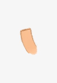 Échantillon de fond de teint crémeux dans une teinte beige chaud, présentant une texture lisse avec des accents de poudre légèrement dispersés autour du bord.