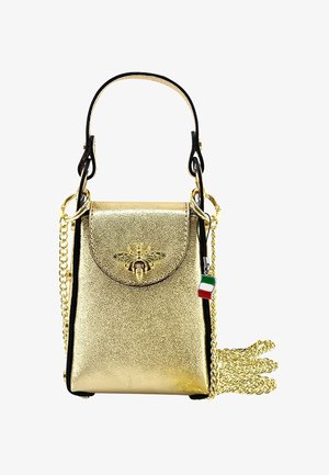 Sac à main métallique doré avec un emblème d'abeille, une bandoulière noire, des détails en chaîne et un petit charme en forme de drapeau italien. Texture lisse et forme rectangulaire.
