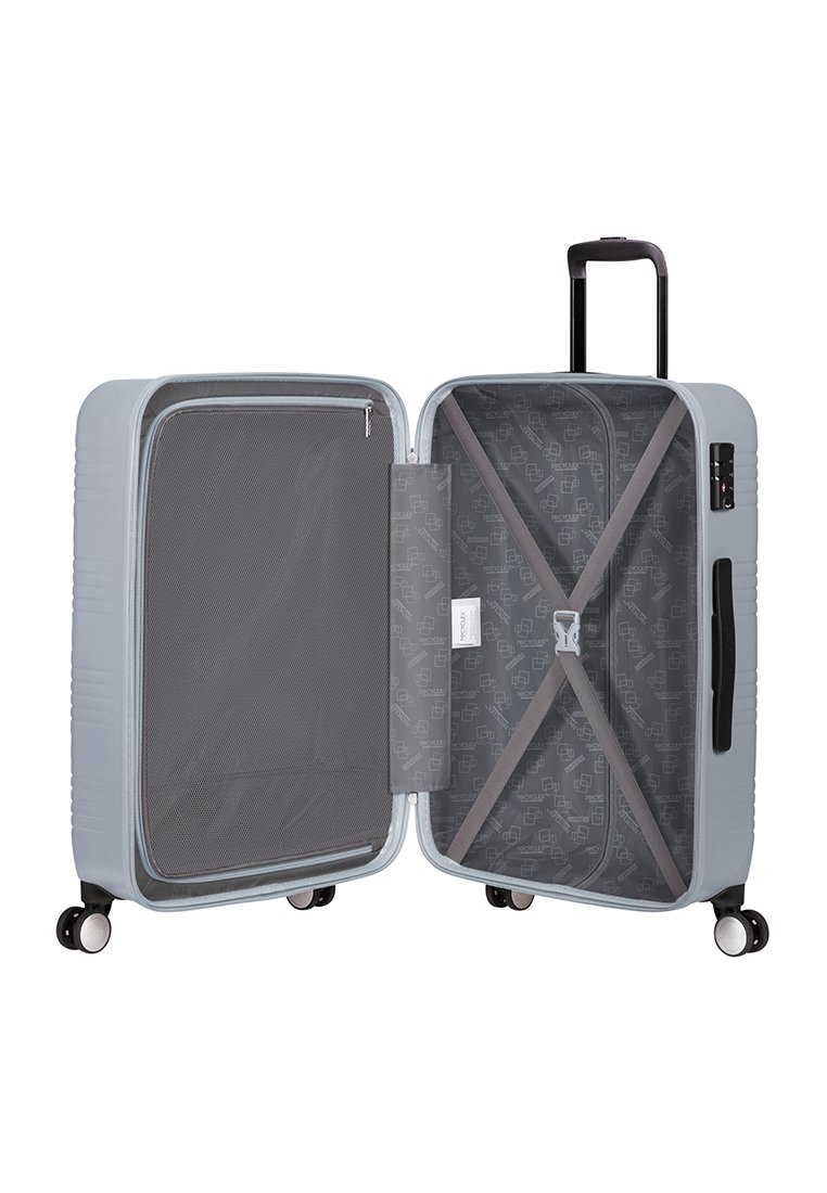 Maleta rígida de color gris claro con un compartimento con cremallera y correas elásticas; cuenta con cuatro ruedas para movilidad y un mango retráctil.
