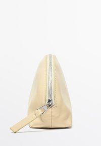 Cytrynowożółty skórzany woreczek z srebrnym zamkiem błyskawicznym. Posiada płaską podstawę i smukły kształt, idealny do organizacji. Dodatki to mała pętla.