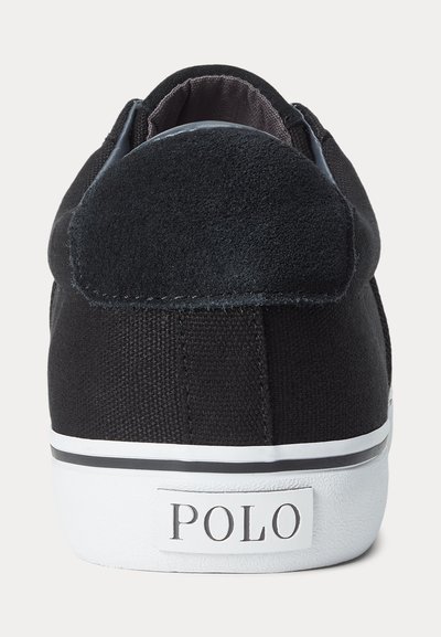 Melns auduma sporta apavu ar zamšādas papēža siksniņu un baltu gumijas zoli, kuras aizmugurē redzams "POLO" logotips.