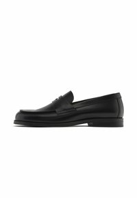 Schwarze Lederloafer mit einer runden Zehenpartie, Steppnähten und einem dekorativen Lederriemen über dem Vorderfuß; flache Gummisohle.