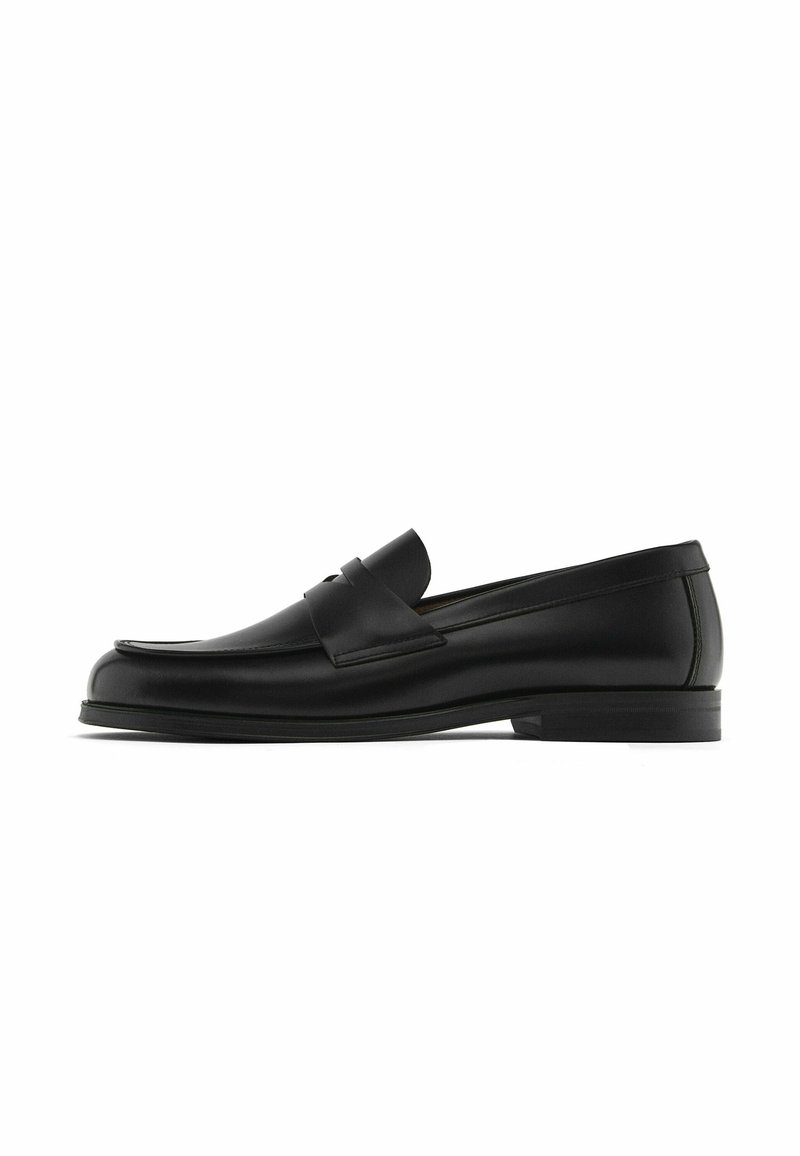 Schwarze Lederloafer mit einer runden Zehenpartie, Steppnähten und einem dekorativen Lederriemen über dem Vorderfuß; flache Gummisohle.