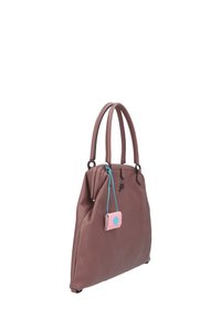 Sac à main en cuir marron avec deux poignées, une fermeture éclair et une petite étiquette rose avec un point bleu. Fini texturé, design structuré.