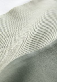 Textil világoszöld, bordázott mintával és enyhén sötétebb zöld, sima anyaggal; lágy, finom színátmenet.