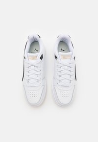 Hvide sneakers med en glat læderoverdel, sorte sideaccenter og teksturerede snørebånd. Har perforeret tå og guld "Puma" branding på tungen.