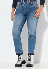 Light blue high-waisted jeans with a relaxed fit, featuring a classic five-pocket design and rolled cuffs, paired with silver lace-up boots.