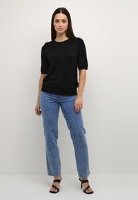 Top corto a maniche corte nero in maglia abbinato a jeans in denim azzurri a vita alta e sandali neri con tacco a strappi. Design semplice e pulito.