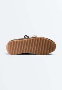 Semelle de chaussure marron avec des rainures horizontales profondes pour une bonne adhérence, vue de dessous sur fond blanc.