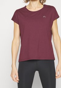 Burgundy kortärmad tränings t-shirt med rund halsringning och en liten logo på vänster bröst. Tillverkad av mjukt, andningsbart tyg.