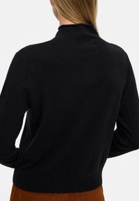 Czarny, dzianinowy sweter z wysokim dekoltem, prążkowanymi mankietami i dolną krawędzią. Gładka tekstura i dopasowany fason. Widok z tyłu, bez wzorów czy zdobień.